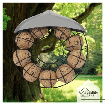 Ein hängender Vogelfutterspender mit einem kreisförmigen schwarzen Drahtdesign, das zwölf Futterbälle hält, vor einem üppig grünen Hintergrund.