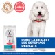 Un chien blanc duveteux avec un collier rouge se tient à côté d'un sac de nourriture pour chien Hill's Science Plan, étiqueté "Hypoallergénique" et "Sans Céréales."