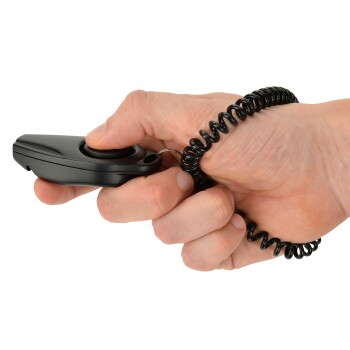 Een hand die een zwarte clicker voor huisdiertraining vasthoudt met een opgerolde polsband, klaar voor gebruik bij het trainen van huisdieren.