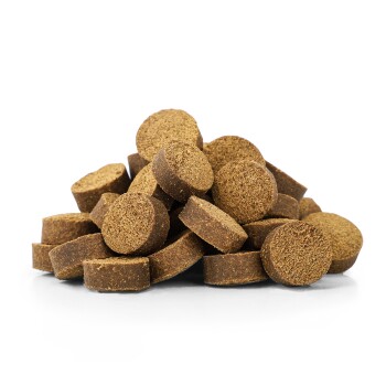 Ein Haufen runder, brauner Haustier-Nahrungsergänzungsmittel oder Leckereien, die ihre strukturierte Oberfläche vor einem weißen Hintergrund zeigen.
