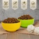 Zwei Schalen mit braunem Futter, eine gelbe und eine grüne, mit weißen Seilspielzeugen. Text: "Getreidefrei", "Hoher Proteingehalt", "Fettarm", "Vitamine A, E, D3."