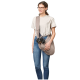 Eine Person in einem hellen T-Shirt und Jeans hält einen kleinen Hund in einer beigen Tragetasche, die eine praktische Transportmöglichkeit für Haustiere zeigt.