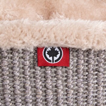 Nahaufnahme eines gemütlichen Haustierbettes mit einer weichen beigen Fleece-Innenseite und einem gewebten grauen Äußeren, mit einem roten Etikett, das ein schwarzes Ahornblatt-Logo zeigt.