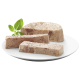 Trois morceaux de pâté pour animaux de compagnie sur une assiette blanche, garnis d'une feuille de basilic frais, montrant une texture lisse et charnue.