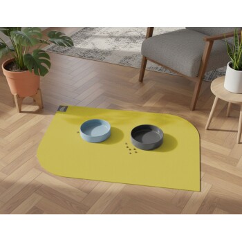 Futternapfstation mit blauen und grauen Näpfen auf einer gelben Matte, auf Holzboden neben Pflanzen und Stuhl platziert.