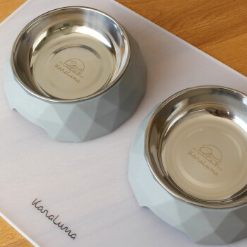 Zwei moderne Futterschalen für Haustiere mit einer geometrischen grauen Silikonbasis und Edelstahl-Einsätzen, mit der Marke "kanaluna" innen eingraviert.