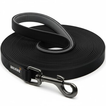 Schwarze Hundeleine ordentlich aufgerollt, mit einem stabilen Clip und einem Etikett mit der Aufschrift "RUDELKÖNIG" mit einem Kronenlogo.