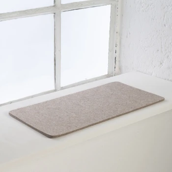 Eine weiche, beige Haustiermatte auf einer weißen Fensterbank, mit natürlichem Licht, das die Szene beleuchtet.