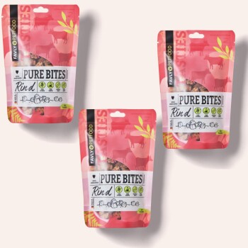 Drei Taschen mit "Pure Bites Rind" Haustierleckereien, mit einem rosa Hintergrund und Kuhsilhouetten sowie Nährstoffsymbolen auf der Vorderseite.