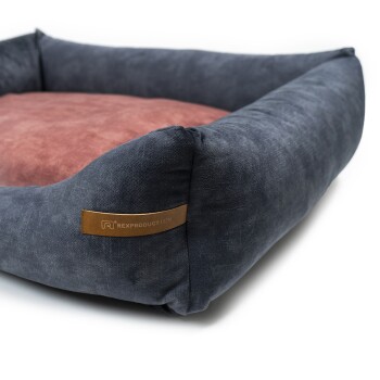 Eine gemütliche Haustierliege mit einem dunkelblauen Äußeren und einem weichen rosa Inneren, mit einem Lederetikett, das "RexProduct.com" liest.