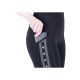 Nahaufnahme einer Hand, die ein Smartphone in die Seitentasche einer schwarzen Leggings mit einem dekorativen weißen Muster steckt.