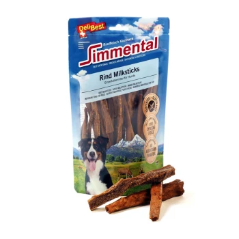 Eine Tüte DeliBest Simmental Rindfleisch-Milchsticks für Hunde, mit einem schwarz-weißen Hund auf der Vorderseite, mit drei Sticks davor.