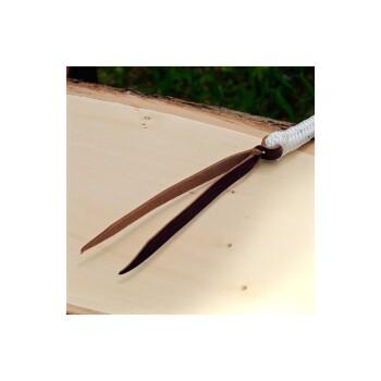 Nahaufnahme eines braunen Lederbands, das an einem weißen Seil befestigt ist und auf einer hellen Holzoberfläche mit grünem Gras im Hintergrund ruht.