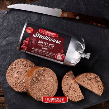 FLEISCHESLUST Steakhouse 'Büffel Pur / Pure Buffalo' Tierfutterrolle, in Scheiben geschnittene Pastetenrunden auf Schiefer mit Messer.