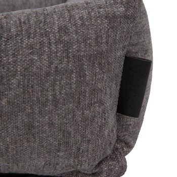 Nahaufnahme eines weichen, grauen Hundebettes mit strukturiertem Stoff und einem schwarzen Etikett mit dem Markennamen.