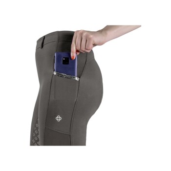 Nahaufnahme einer Frauenhand, die ein Smartphone in die Gesäßtasche von enganliegenden grauen Reithosen steckt, mit einem dekorativen Logo.