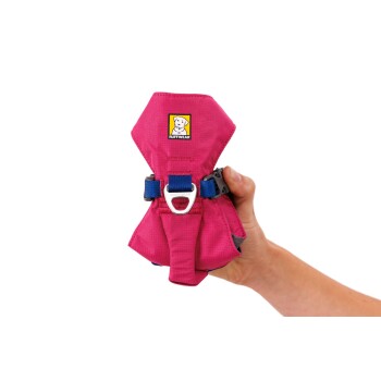 Eine Person hält ein pinkes Hundegeschirr mit einem blauen Riemen und einem Metallclip, mit dem Logo 'RUFFWEAR' oben.