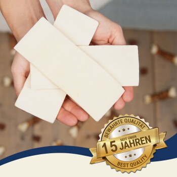 Eine Person hält vier rechteckige weiße Hundekauartikel in ihren Händen, mit einem goldenen Abzeichen, das "Beste Qualität seit über 15 Jahren" angibt.