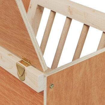 Nahaufnahme einer hölzernen Haustierkiste mit schrägem Dach, ausgestattet mit einem goldenen Riegel und Holzstangen zur Belüftung.