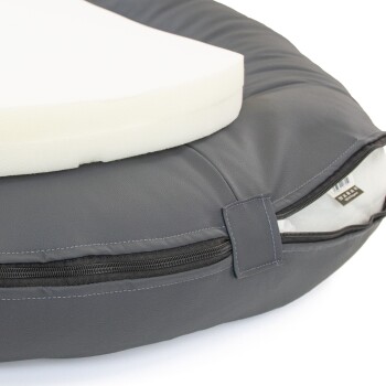 Eine Nahaufnahme eines grauen Haustierbettes mit einem abnehmbaren Schaumkissen, mit einem sichtbaren Reißverschluss an der Seite für eine einfache Reinigung.