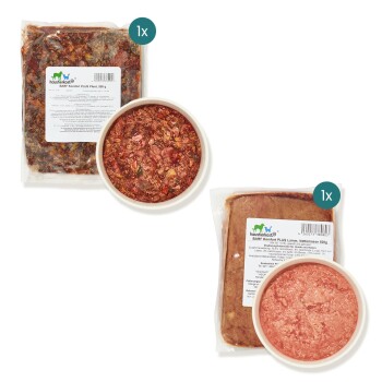 Zwei HausTierkost-Tierfutterpakete: eines "BARF Komfort PLUS Lamm" (500g Lamm) und ein anderes mit einer gemischten Fleischmischung in einer Schüssel.