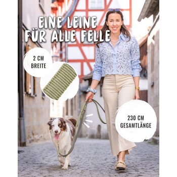 Frau geht mit Hund in der Stadt und hält eine olivgrüne Leine; Text: 'Eine Leine für alle Felle', '2 cm Breite', '230 cm Gesamtlänge'.