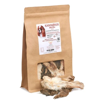 Braune Papiertüte mit Hundeleckerlis, beschriftet mit 'KANINØRER MED PELS', mit einem Fenster, das die Leckerlis im Inneren zeigt, und einem Hundebild auf der Vorderseite.