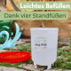 Weißer Tierwasserspender auf vier Füßen gießt in eine rote Schale auf dem Gras; Text: 'Leichtes Befüllen, Dank vier Standfüßen'.