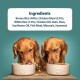 Two golden retrievers eating from white bowls on a wooden surface, with a list of ingredients above.