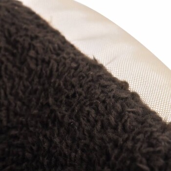 Nahaufnahme eines weichen, dunkelbraunen Haustierbettstoffs mit einer strukturierten Oberfläche, die sich von einem glatten beigen Rand abhebt.