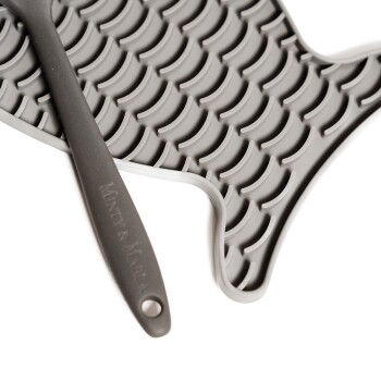 Graue Silikon-Tierfuttermatte in Fischform, mit einer strukturierten Oberfläche, mit einem dunkelgrauen Silikonlöffel beschriftet "Mint & Manna."