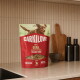 Sac rouge CARNILOVE de friandises molles à la caille sur un plan de travail de cuisine ; l'étiquette indique «Caille tendre», «Pour chiens adultes», «Pas de colorants artificiels».