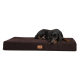 Ein schwarzer Dobermann liegt bequem auf einem großen, dunkelbraunen Hundebett mit einem kleinen Logo-Tag.
