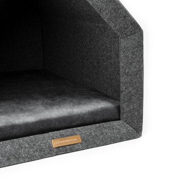 Ein gemütliches graues Haustierhaus mit einem weichen schwarzen Kissen innen, mit einem Lederetikett, das 'rexproduct.com' liest.