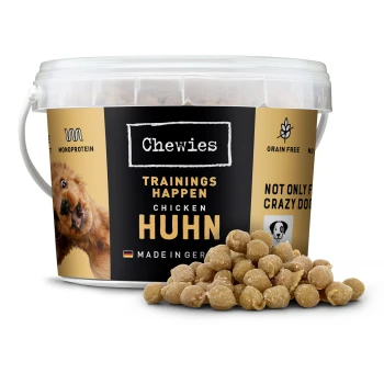 Behälter mit Chewies Hundetraining Leckerlis, mit einem Hundebild, beschriftet mit "Chicken Huhn", getreidefrei, mit verstreuten Leckerlis davor.