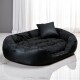 Schwarzes ovales Haustierbett mit gepolsterten Seiten und passendem schwarzem Kissen auf weißem Marmorboden.