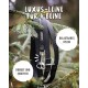 Schwarze Luxus-Hundeleine hängt an einem Kieferzweig mit Metallclip; sichtbarer Text: 'Luxus-Leine für 4 Beine', 'Belastbares Nylon', 'Robust und rostfrei'.