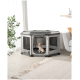 Ein kleiner Welpe sitzt in einem grauen Haustierspielzaun mit Netzseiten, der auf einem hellen Boden neben einem gemütlichen Sofa und einer Pflanze platziert ist.