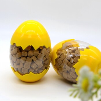 Gelbe, eiförmige Behälter gefüllt mit braunen Hundeleckerlis, einer stehend und einer liegend auf weißem Hintergrund.