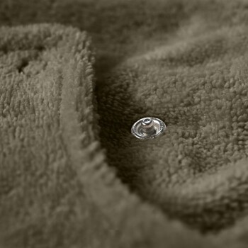 Nahaufnahme einer weichen, olivgrünen Haustierdecke mit einem sichtbaren silbernen Druckknopf, die ihre gemütliche Textur hervorhebt.