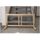 Porte pour animaux en bois avec des barres en métal, placée en bas d'un escalier, avec un design simple et une construction robuste.