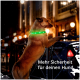 Ein Hund mit einem leuchtend grünen Halsband steht auf seinen Hinterbeinen an einem Geländer in einem schwach beleuchteten städtischen Bereich. Text: "Mehr Sicherheit für deinen Hund."