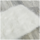 Ein flauschiges weißes Haustierbett auf einem Holzboden, das seine weiche Textur und gemütliche Erscheinung zeigt.