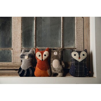 Vier pluche dieren speelgoed zitten op een houten vensterbank: een wasbeer, een vos, een beer en een uil, elk met unieke texturen en kleuren.