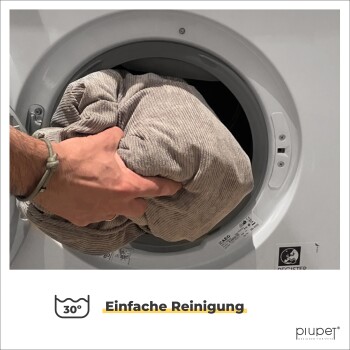 Eine Hand, die eine große, zerknitterte graue Decke in eine Waschmaschine legt, mit dem Text 'Einfach Reinigung' und einem Waschsymbol, das 30°C anzeigt.