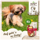 Kleiner flauschiger Hund läuft auf Gras neben Bettys Landhausküche Hundefutterpackung mit der Aufschrift "Rind" mit Kartoffel, Kürbis und Birne.