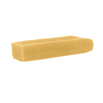 Ein rechteckiges Stück hellgelbes Hundekauspielzeug, das einem Stück Käse ähnelt, mit einer strukturierten Oberfläche.