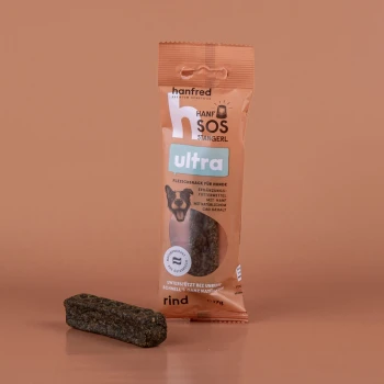 Hundeleckerli-Verpackung mit der Aufschrift "hanfred Hanfsos Stangerl ultra" und einem Foto eines Hundes, mit Text über Hanf und natürlichen CBD-Gehalt.