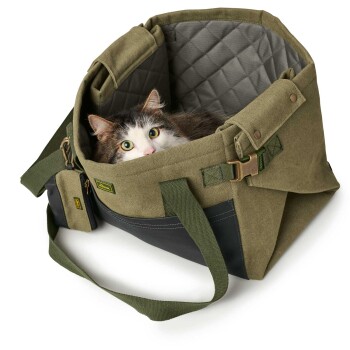 Eine stilvolle olivgrüne Haustiertragetasche mit einem gesteppten Innenraum, mit einem schwarzen Boden, verstellbaren Riemen und einer kleinen Reißverschlusstasche.