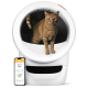 Eine verspielte orange getigerte Katze steht in einer modernen weißen Katzentoilette, neben ihr ein Smartphone, das die Whisker-App anzeigt.